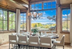 A dining room with a table set for six, large windows, and a chandelier. - Private Estate 🏔️ 9,400 sq ft ✨ Game Room 🎱 Steam Sauna 💦 1.5 Acres 🧖‍♀️ Spa (Silverthorne)