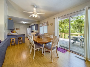 A spacious kitchen with a dining area, wooden flooring, and a large sliding glass door leading to an outdoor deck.
