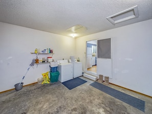 A laundry room with a washing machine, dryer, and shelves with cleaning supplies.