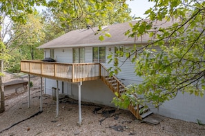 A house with a wooden deck and a staircase leading to a second-story window.