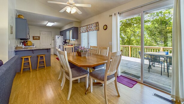 A spacious kitchen with a dining area, wooden flooring, and a large sliding glass door leading to an outdoor deck.