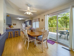 A spacious kitchen with a dining area, wooden flooring, and a large sliding glass door leading to an outdoor deck.
