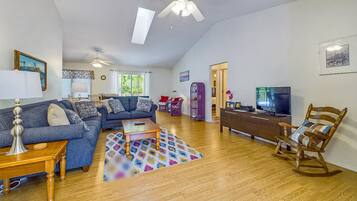 A spacious living room with a ceiling fan, a sofa set, a coffee table, a TV, and a rocking chair.
