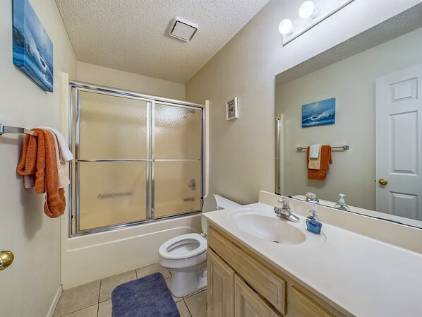 A bathroom with a glass shower enclosure, a white sink, and a toilet.