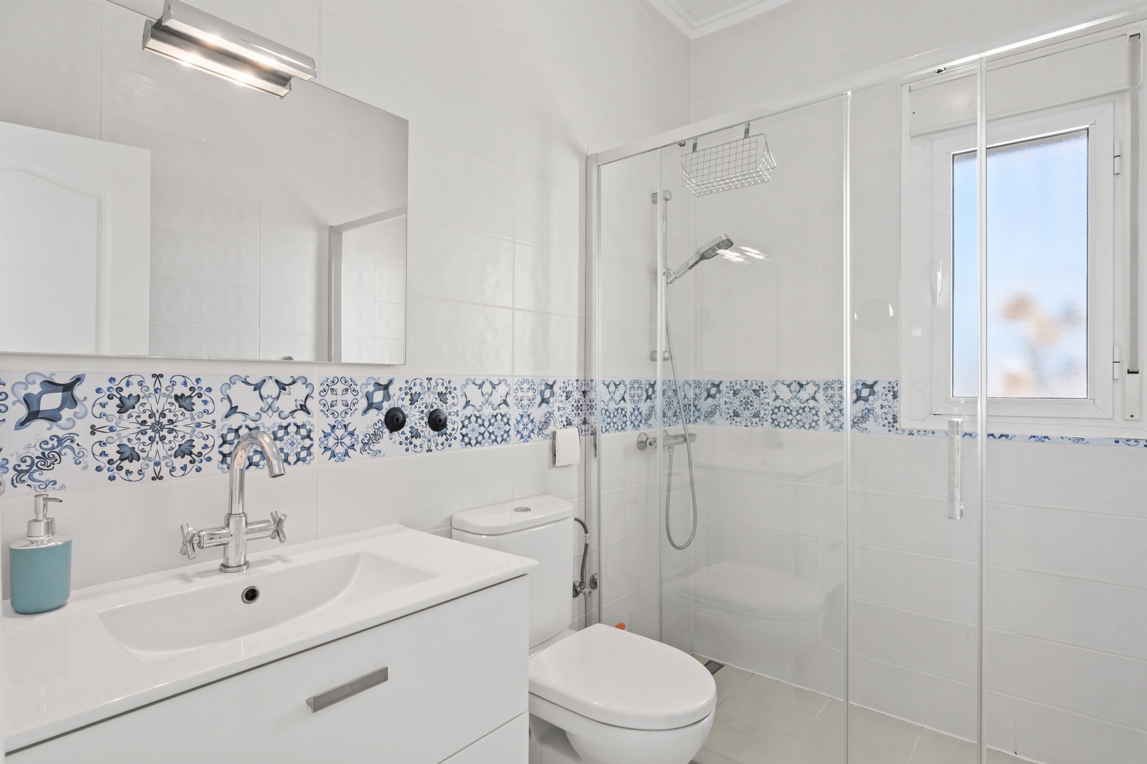 A modern bathroom with a white sink, toilet, and shower.