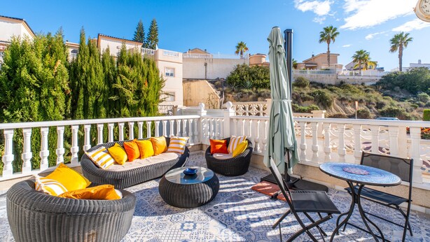 Eine Terrasse mit Korbmöbeln, einem Tisch und einem Stuhl.