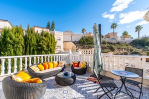 Une terrasse avec des meubles en osier, une table et une chaise.