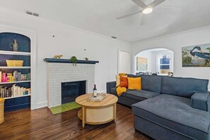 Una sala de estar con chimenea, un sofá, una mesa de centro y una estantería.