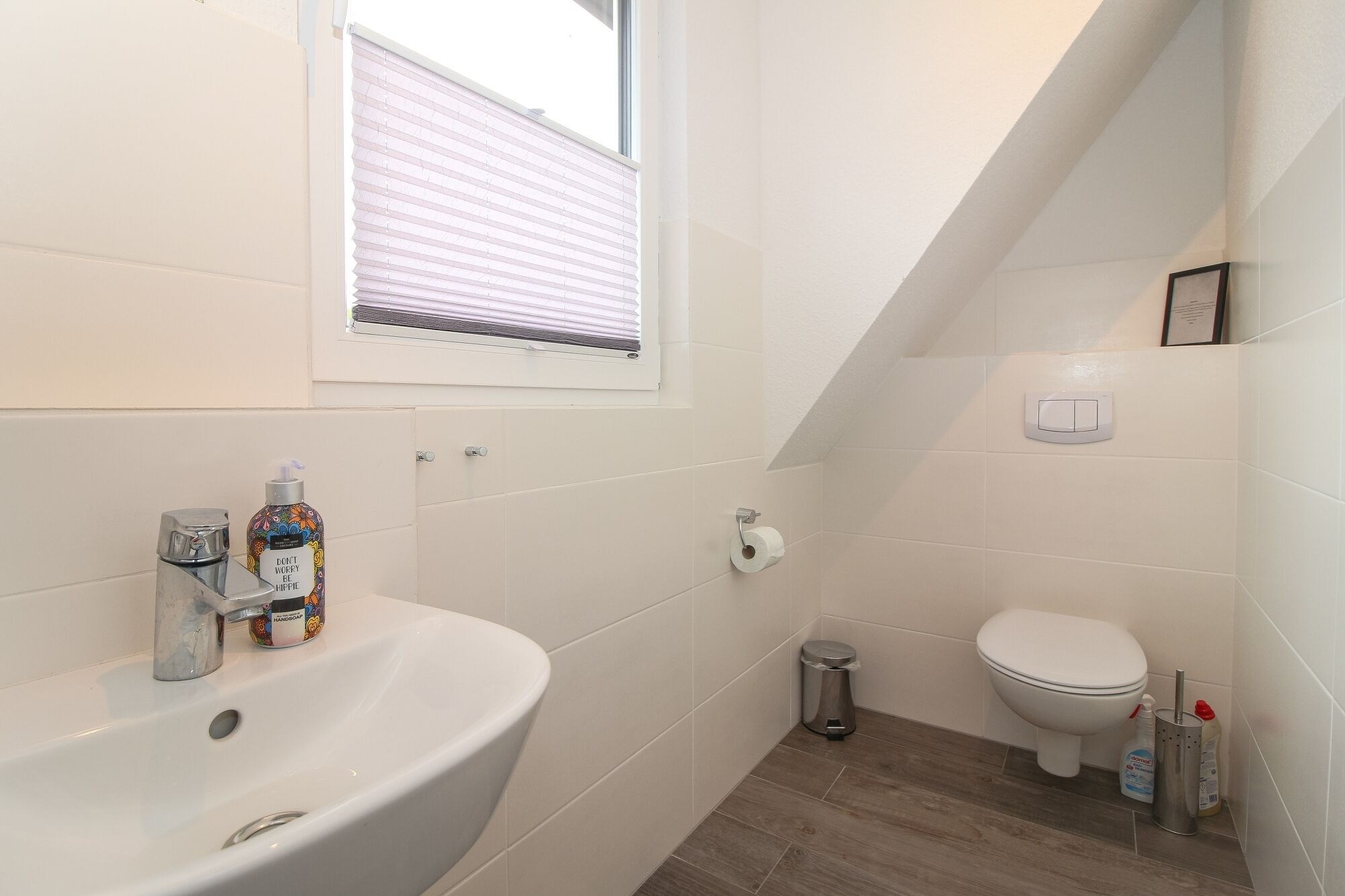 A small, modern bathroom with a white sink, toilet, and shower.
