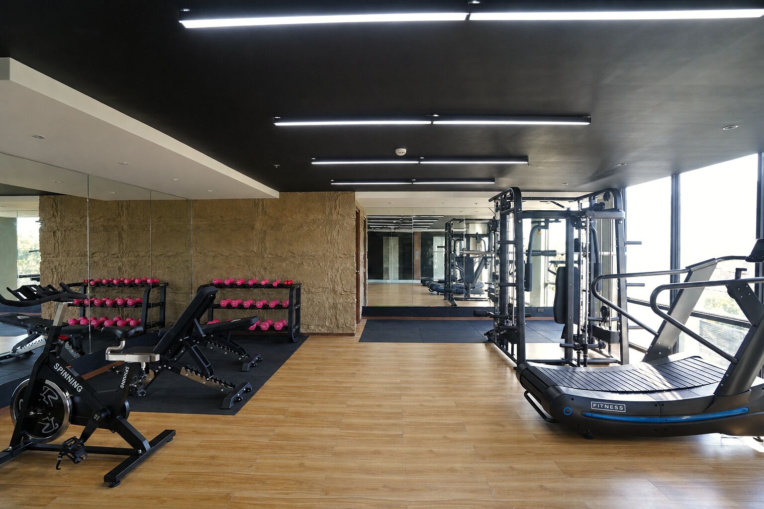 A gym with cardio equipment, weight machines, and dumbbells.