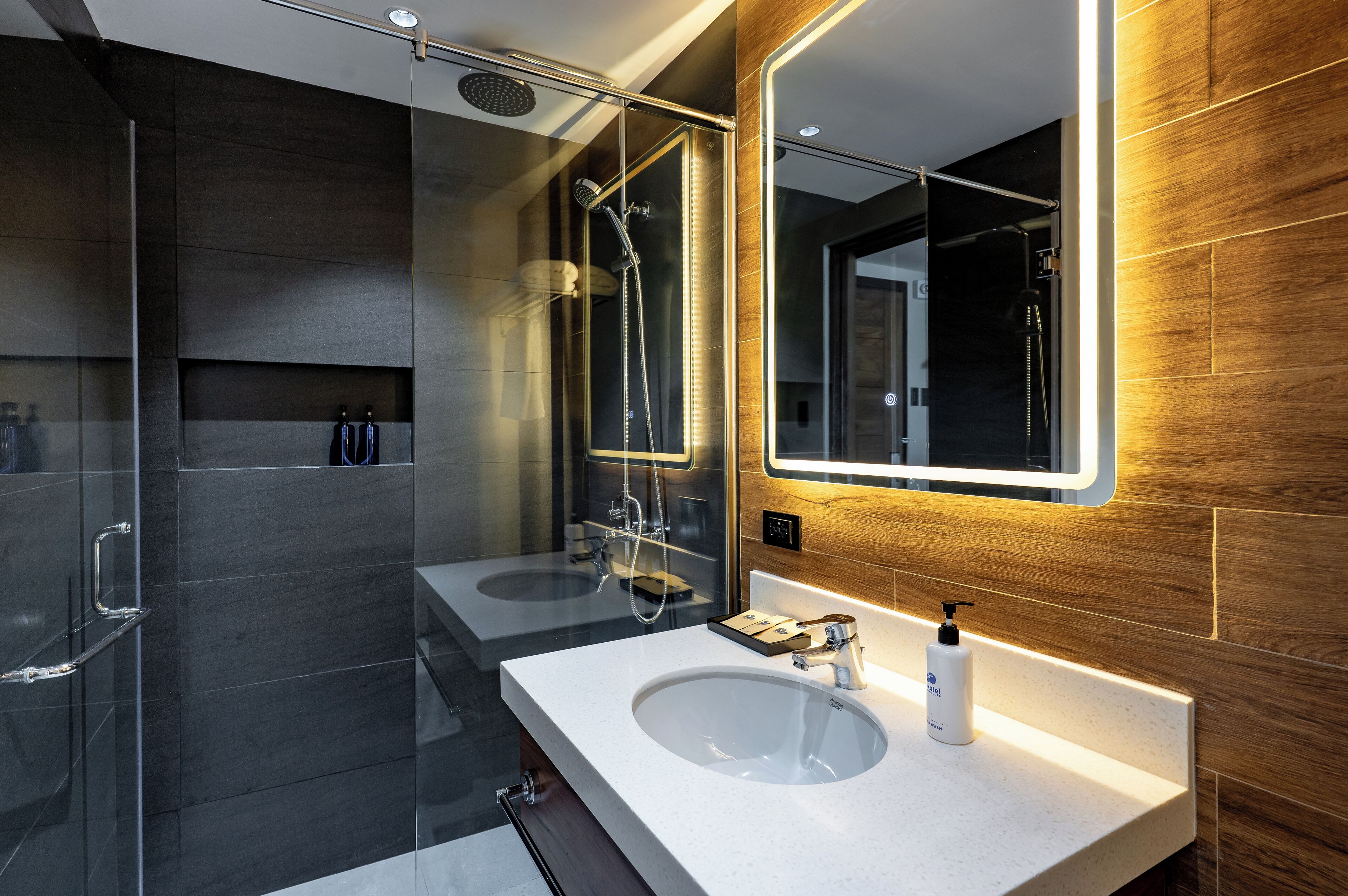 A modern bathroom with two sinks, a glass shower enclosure, and a large mirror.