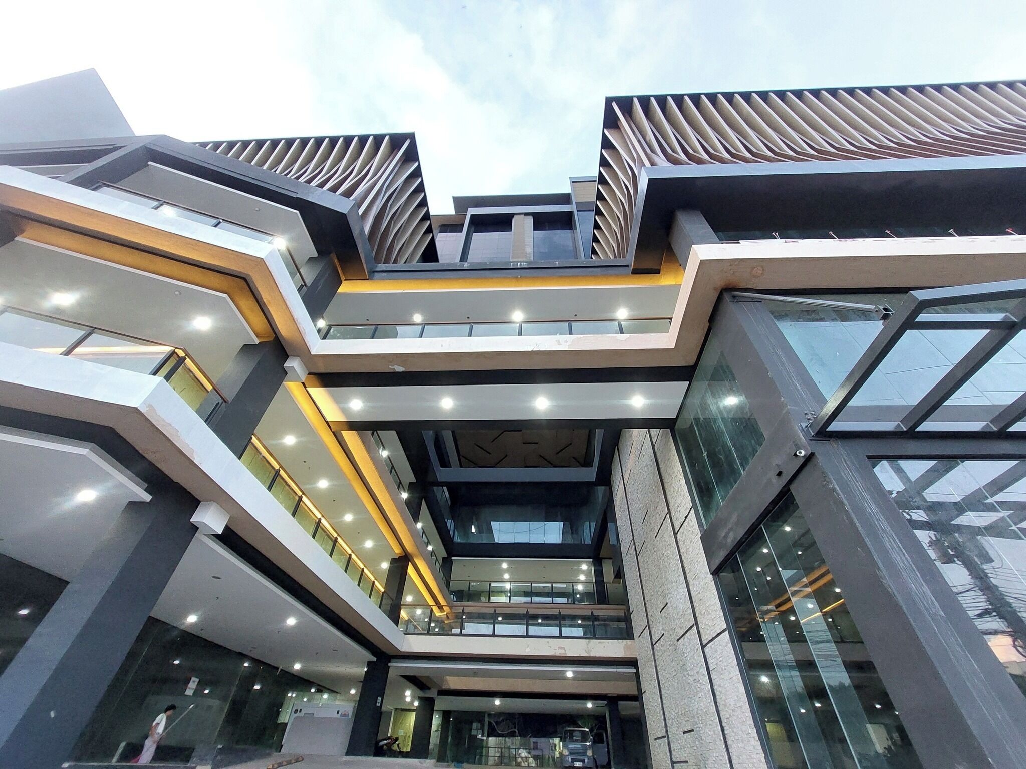A modern multi-story building with a central atrium, glass railings, and a geometric facade.