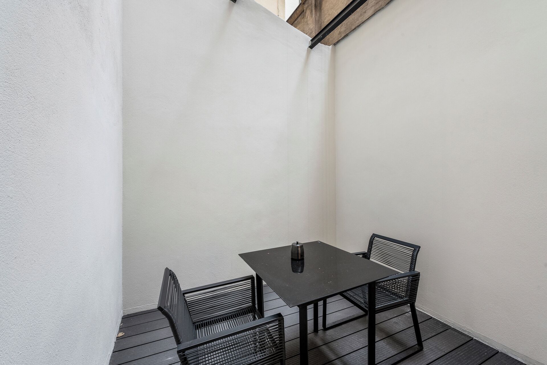 A small outdoor patio with a square table and two chairs.