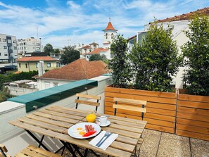 Uma área de refeições ao ar livre com uma mesa posta para café da manhã, incluindo ovos, salsichas e tomates.