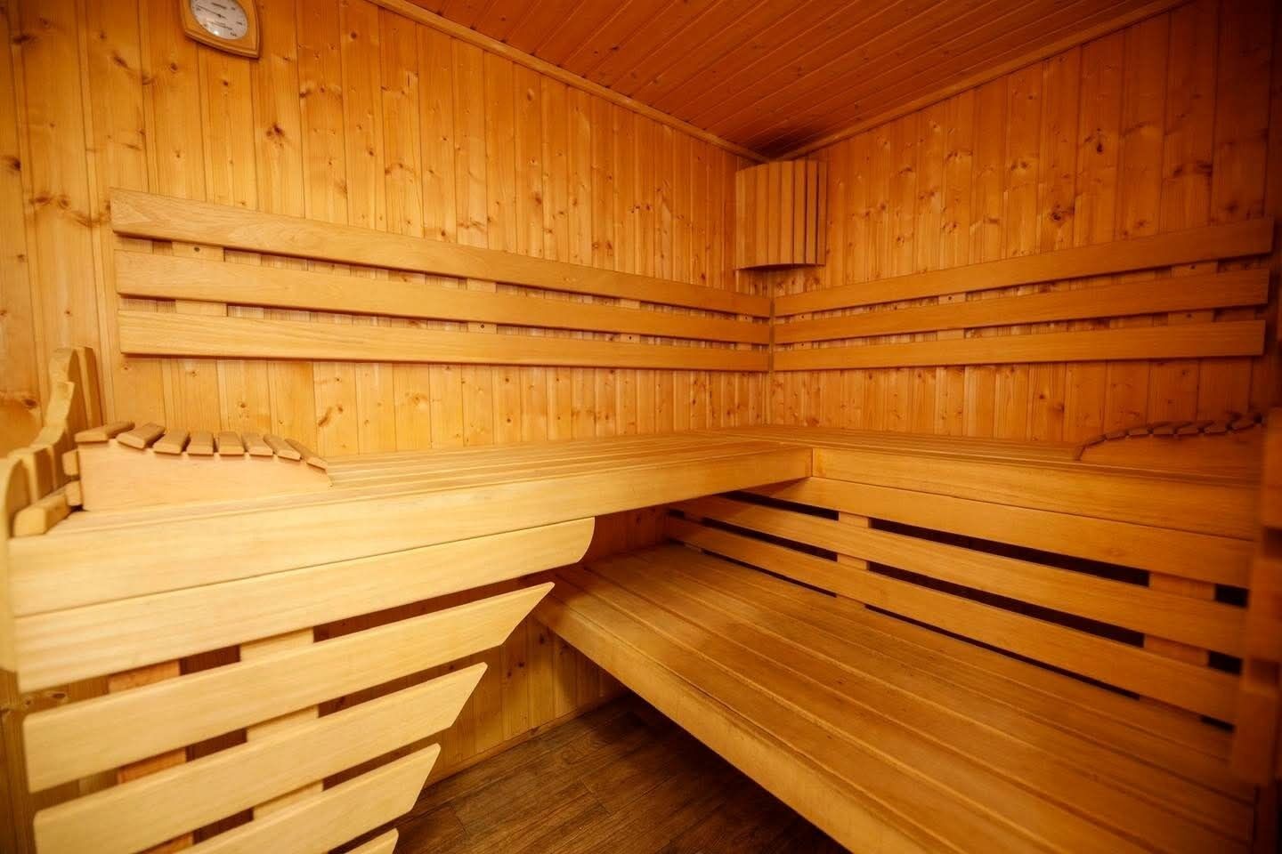 Eine Sauna mit Holzbänken und -wänden, einer Uhr an der Wand und einem kleinen Fenster.