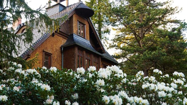 Une maison traditionnelle en bois, dotée d’un toit à forte pente, d’une cheminée bien visible et d’un clocher.