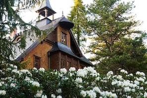 Una casa de madera tradicional con techo empinado, chimenea visible y campanario.