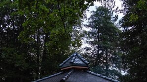 Un kiosque doté d’une base en pierre et d’un toit en bois, entouré d’un mur en pierre et d’une terrasse en bois.