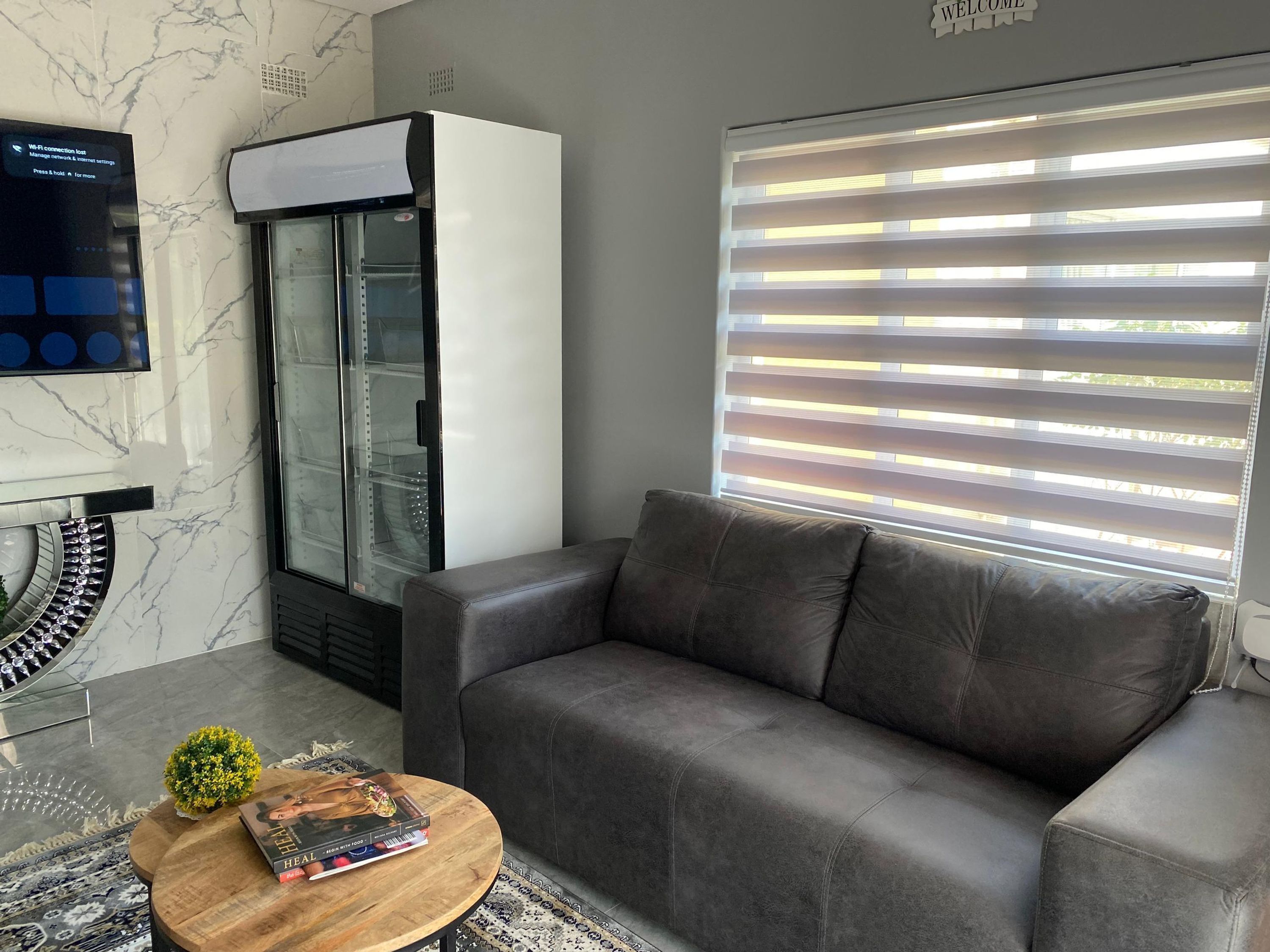 A living room with a grey sofa, a coffee table with a book, a TV, and a wall-mounted air conditioner.