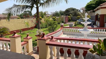 A balcony with a stone floor, white balustrades, and a white fountain.
