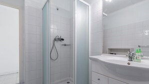 A bathroom with a shower, a sink, and a mirror. - Spacious Studio Apartment Close to The Martinez - 2313 (Cannes)