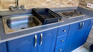 Una cucina con lavello in acciaio inossidabile, un cestino di plastica nera e piano cottura integrato.