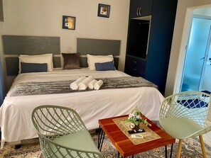 A hotel room with a bed, two chairs, a small table with a vase, and a wardrobe. - Modern Studio Apartment in a Central New Chadcombe - 2318 (Harare)