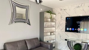 Un saló modern amb un sofà gris, un mirall decoratiu, un televisor que mostra un error de càrrega i una paret amb dibuixos de marbre.