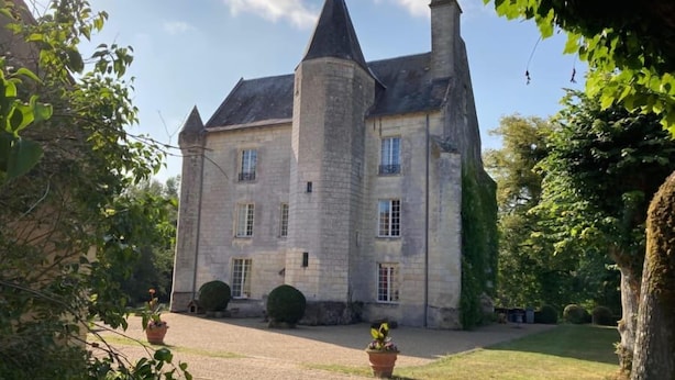 A large, historic stone building with a central tower, surrounded by a well-maintained lawn and potted plants. - Château de Ré (Le-Petit-Pressigny)