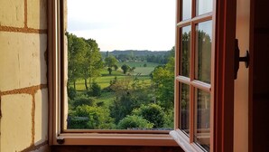 A corner room with a large window overlooking a green landscape. - Château de Ré (Le-Petit-Pressigny)
