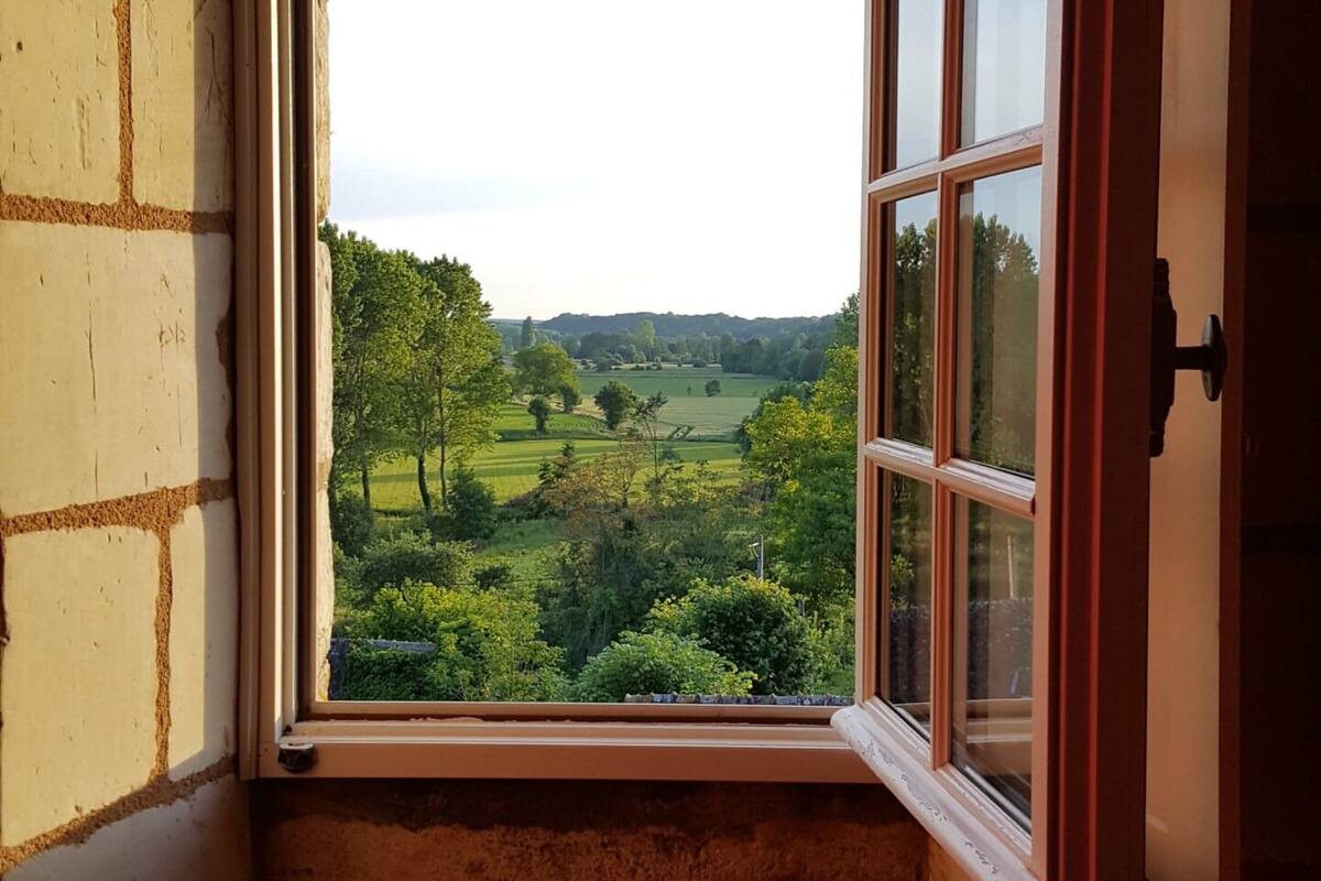 Une chambre d’angle dotée d’une grande fenêtre donnant sur un paysage verdoyant.