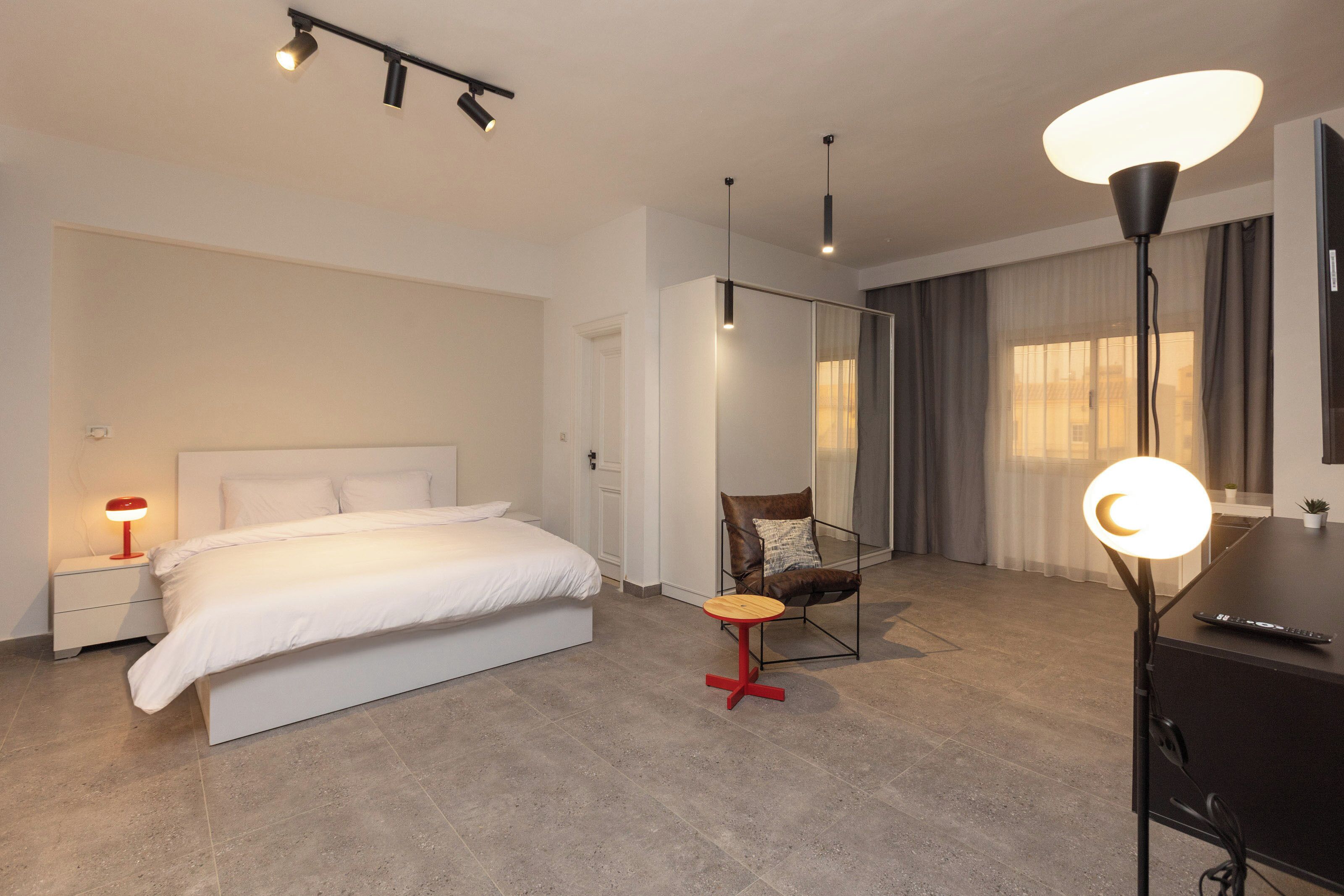 Une chambre d’hôtel moderne équipée d’un grand lit, d’un bureau, d’une chaise et d’un miroir.