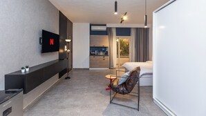 A modern hotel room with a flat-screen TV, a sofa, a small table, a bed, and a large window. - Host Prime Boutique hotel 04 (New Cairo)