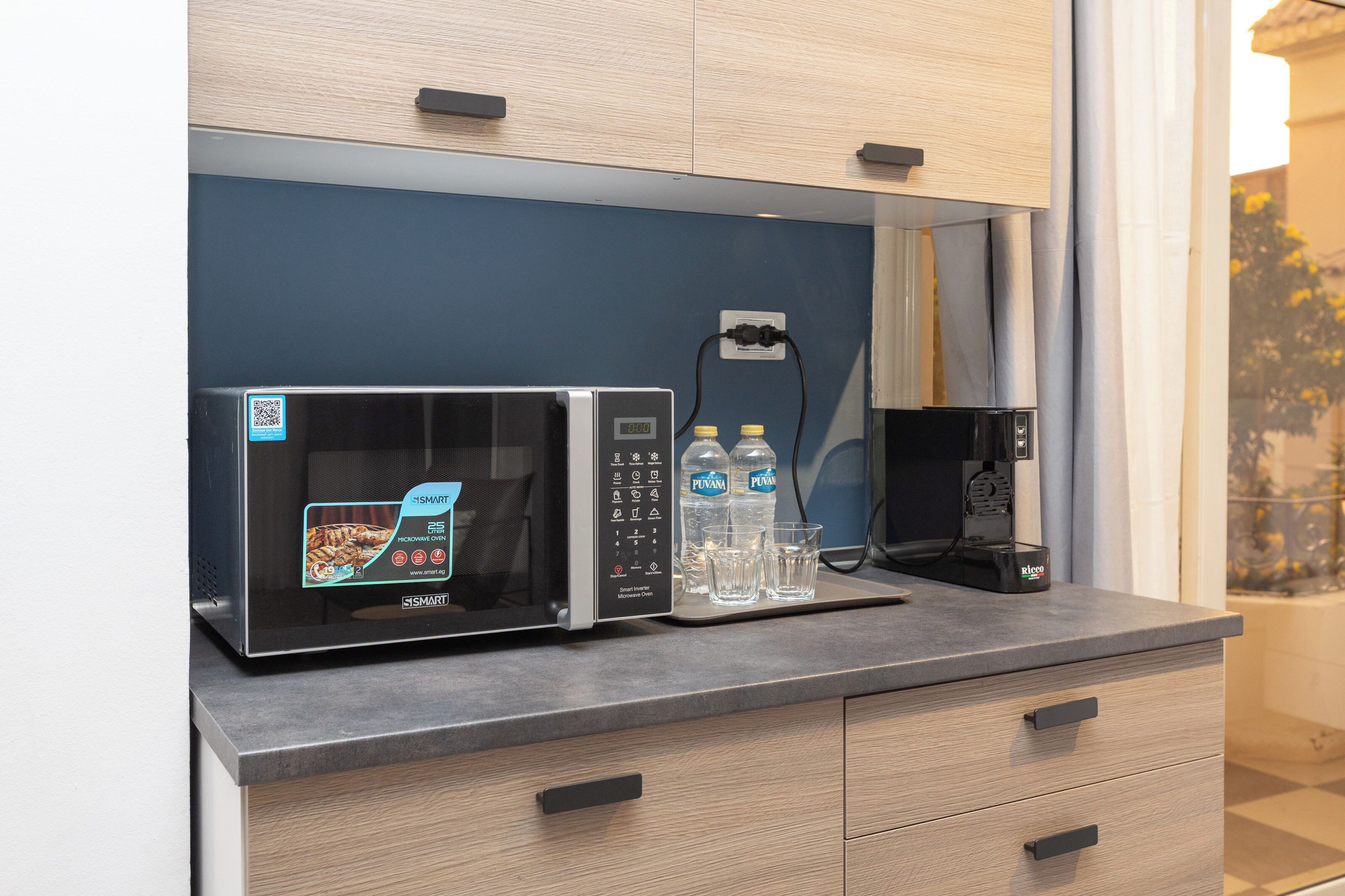 A modern kitchen with a microwave, a coffee maker, and two bottles of water on the counter.