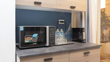 A modern kitchen with a microwave, a coffee maker, and two bottles of water on the counter.