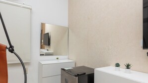 A modern bathroom with a white sink, a mirror, a small refrigerator, and two potted plants on the counter. - Host Prime Boutique Hotel 01 (Shurtah al-Dakhlah)