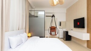 A modern hotel room with a large bed, a hanging chair, a TV, and a minibar. - Host Prime Boutique Hotel 01 (Shurtah al-Dakhlah)
