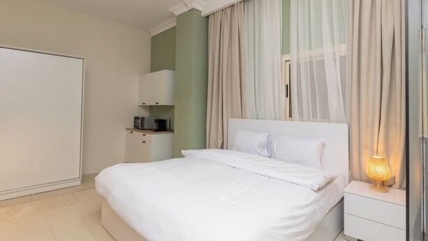 A neatly arranged hotel room with a bed, bedside table, and a wardrobe. - Host Prime Boutique Hotel 01 (Shurtah al-Dakhlah)