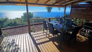 A wooden deck with a table and chairs, overlooking a scenic view of the ocean. - Exceptional sea view Quiet, swimming pool and nature 20 minutes from Cannes (Saint-Raphaël)