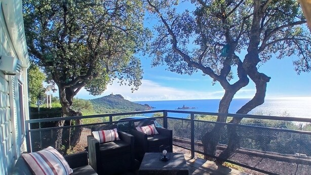 A deck with outdoor furniture, a view of the sea, and a mountainous landscape. - Exceptional sea view Quiet, swimming pool and nature 20 minutes from Cannes (Saint-Raphaël)