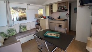 A compact living space with a kitchenette, a dining area, and a seating area with a sofa and a table. - Exceptional sea view Quiet, swimming pool and nature 20 minutes from Cannes (Saint-Raphaël)
