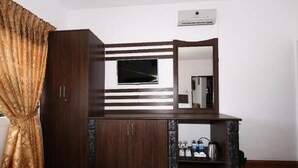 A room with a wooden desk, a flat-screen TV mounted on the wall, a mirror, and a shelf with various items. - Nat City Hotel Nuwaraeliya (Nuwaraeliya)