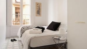 Una habitación de hotel con una cama, una mesita de noche, una ventana y una puerta.