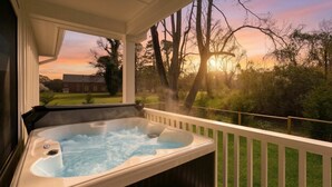 Ein Whirlpool auf einer Holzterrasse mit Blick auf einen Sonnenuntergang und Bäume.