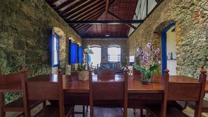 A rustic dining area with stone walls, wooden tables, and chairs. - Historic house in the center of Paraty, with incredible sea views. (Paraty)