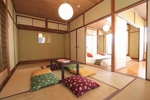 A traditional Japanese room with tatami flooring, a low table, and cushions. - GORAKU Shinfukae 201 (Osaka)