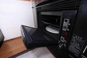 An open microwave with a control panel and a plate inside.