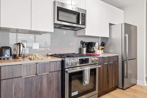 Eine moderne Küche mit Einbau-Mikrowelle, Gasherd, Backofen und Edelstahlkühlschrank.
