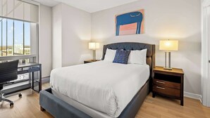Une chambre d’hôtel moderne avec un grand lit, deux tables de chevet avec des lampes, un bureau et une chaise.