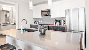 Une cuisine moderne dotée d’un îlot central, d’appareils électroménagers en acier inoxydable et d’un design minimaliste.